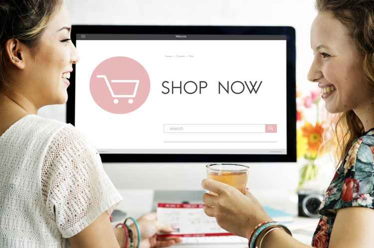 Two girls looking at each other in front of computer with shopping cart created by Redline Company